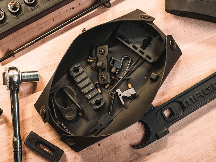 Small Magpul DAKA Magnetic Field Tray filled with misc gun parts on bench with Magpul Armorer’s Wrench